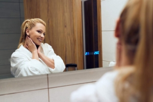 Woman looking at her reflection in a high tech bathroom mirror installed by Shapiro Bathrooms & More