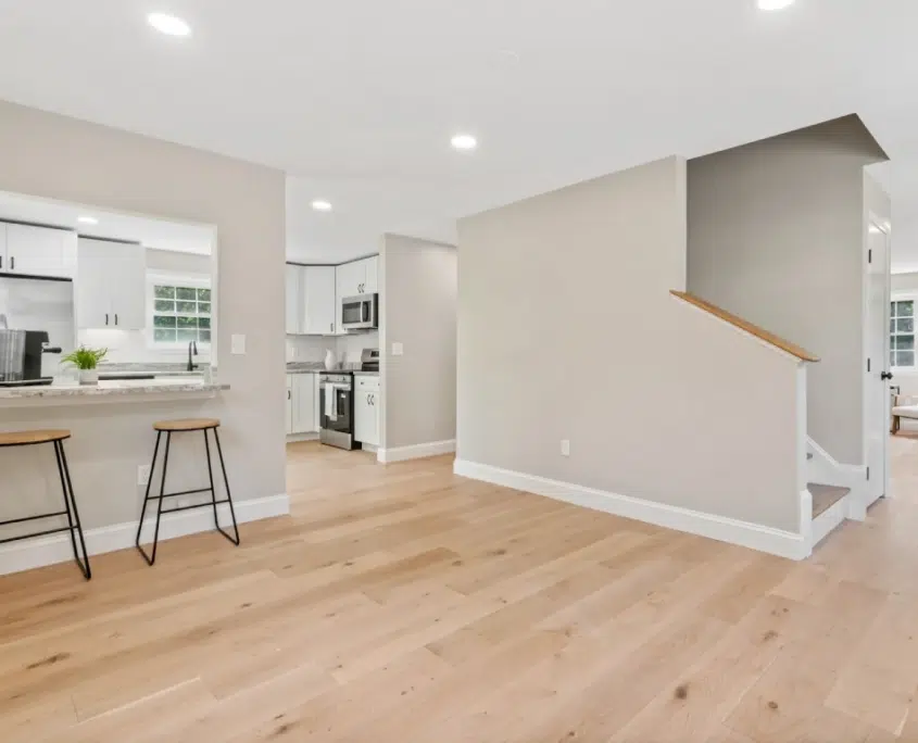An open floor plan kitchen remodel in New Hampshire. Home renovation project includes modern appliances, breakfast bar, recessed lighting, and pine flooring. Call Shapiro Bathrooms & More for your free house renovation cost estimate.