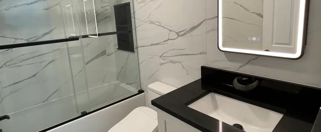 Modern bathroom remodel in Concord, NH featuring a shower-to-tub conversion, white vanity, and an LED smart mirror.