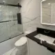 Modern bathroom remodel in Concord, NH featuring a shower-to-tub conversion, white vanity, and an LED smart mirror.