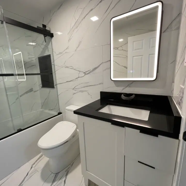 New Hampshire bathroom remodel project showing a premium master bath with a backlit LED mirror, white vanity, black countertop, and a smart bidet toilet.