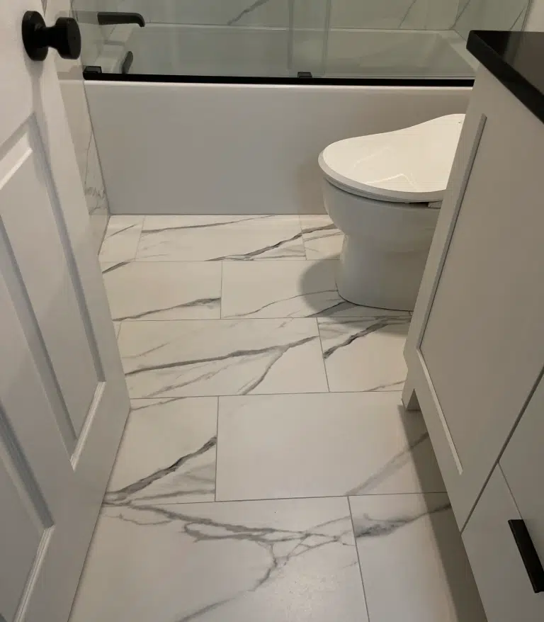 Large-format white and grey marble-look porcelain floor tiles laid in a staggered pattern for a Concord, NH bathroom.