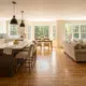 Remodeled open-concept kitchen and living area featuring new oak hardwood floors, natural sunlight, and freshly painted neutral walls in a traditional New Hampshire home, showcasing high-value renovation using the 30 percent rule.