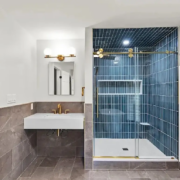 small-bathroom-layout-ideas-new-hampshire Small bathroom layout with a floating white sink, gold fixtures, gray tile wainscot and a navy vertical-tile walk-in shower, an idea for NH homes.